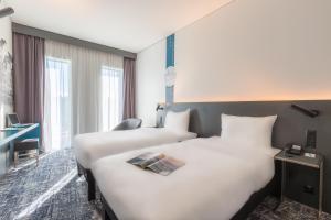 una camera d'albergo con 2 letti e una scrivania di ibis Styles Basel City a Basilea