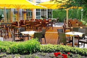 a restaurant with tables and chairs and yellow umbrellas at Seminaris Hotel Lüneburg in Lüneburg