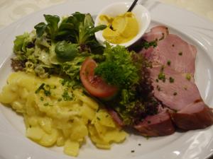 einen Teller mit Fleisch, Kartoffeln und Salat in der Unterkunft Hotel Engel in Endingen