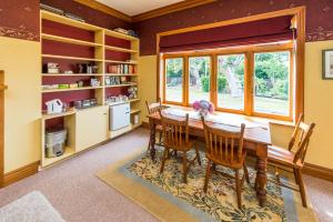 a dining room with a table and chairs and a window at Gumnut House. in Whanganui