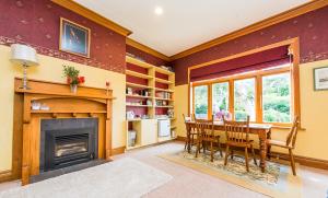 a dining room with a fireplace and a table and chairs at Gumnut House. in Whanganui