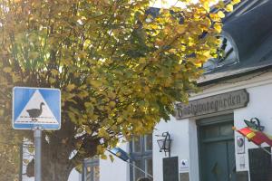 a sign in front of a building with a tree at Skanörs Gästgifvaregård in Skanör med Falsterbo