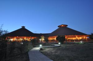 un bâtiment avec des tables et des chaises devant lui la nuit dans l'établissement Kilima Safari Camp, à Amboseli