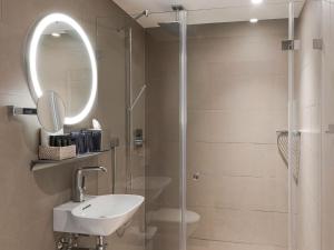 La salle de bains est pourvue d'une douche, d'un lavabo et d'un miroir. dans l'établissement Hotel Savoy, à Berne