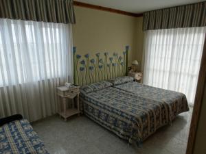 um quarto de hotel com duas camas e duas janelas em Hotel Los Juncos em Noja