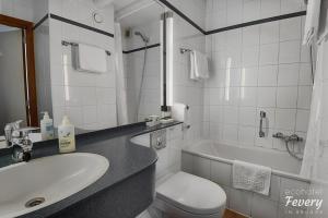 a bathroom with a sink and a toilet and a tub at Hotel Fevery in Bruges