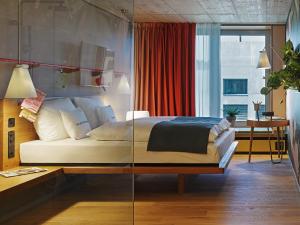 een slaapkamer met een bed met een glazen wand bij 25hours Hotel Langstrasse in Zürich