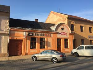 twee auto's geparkeerd voor een gebouw bij Grillbar Penzion & Restaurant in Spišská Nová Ves