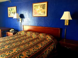 una camera da letto con un letto con pareti blu e due lampade di Crown Inn Grand Prairie a Grand Prairie