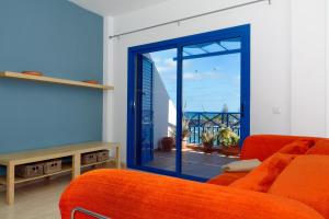 een woonkamer met een oranje bank en een glazen schuifdeur bij Top Charco San Gines Stunning View Lanzarote By PVL in Arrecife