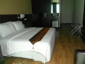 a large white bed with a brown blanket on it at Keoja Hotel in Kuala Belait