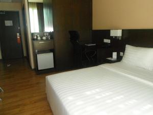 a bedroom with a bed and a desk with a chair at Keoja Hotel in Kuala Belait