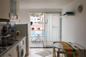 una piccola cucina con tavolo e un balcone con vista di Casa de Hóspedes Porto Pim a Horta