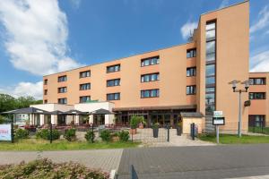 een gebouw met tafels en parasols ervoor bij Montana Parkhotel Marl in Marl