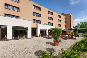 een hotelgebouw met tafels en parasols op een binnenplaats bij Montana Parkhotel Marl in Marl