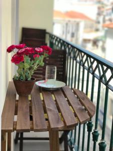 uma mesa de madeira com um vaso de rosas vermelhas numa varanda em São Martinho do Porto Beach Apartment em São Martinho do Porto