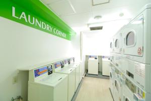 a laundry room with white appliances and a green sign at FLEXSTAY INN Ekoda in Tokyo