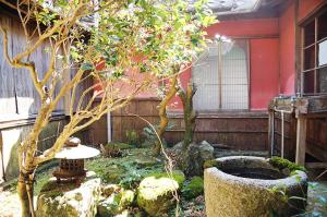 een tuin met een kleine boom en een gebouw bij Taikoji Shukubo Hostel in Ise