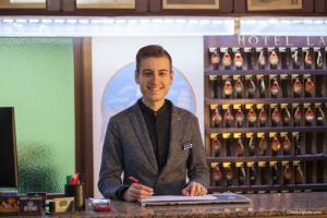 a man standing behind a counter with a pen andepad at Hotel La Pace in Pisa