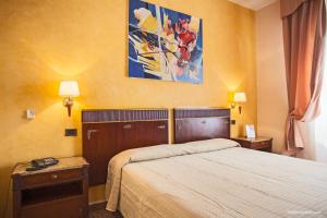 a hotel room with a bed and two tables and a painting at Hotel La Pace in Pisa