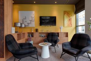 a waiting room with three chairs and a tv at Mercure Hotel Mannheim am Rathaus in Mannheim