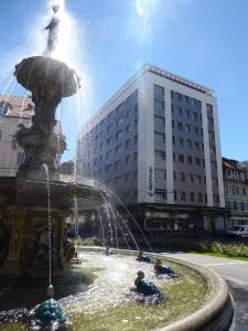 Une fontaine dans une ville avec des gens qui y jouent dans l'établissement Hotel Fleur-de-Lys, à La Chaux-de-Fonds