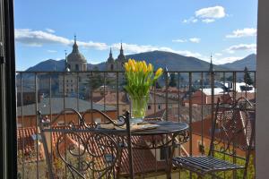 stół z wazą kwiatów na balkonie w obiekcie San Lorenzo Suites w mieście San Lorenzo de El Escorial