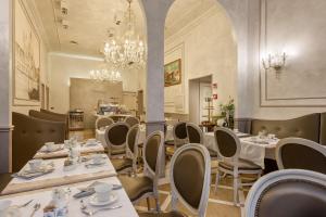 un restaurant avec des tables et des chaises blanches et un lustre dans l'établissement Hotel Ca' dei Conti, à Venise