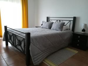 a bedroom with a black bed with pillows on it at Vina's Place in Nazaré