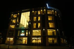 un bâtiment éclairé avec une horloge la nuit dans l'établissement Woodies Bleisure Hotel, à Kozhikode