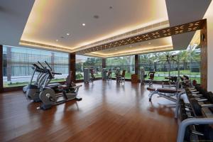 - une salle de sport avec des tapis de course et des équipements de cardio-training dans un bâtiment dans l'établissement Hotel Naveen Lakeside, à Hubli