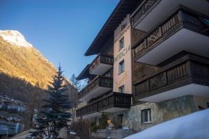 een gebouw met een boom ervoor bij Apartments Patricia in Zermatt