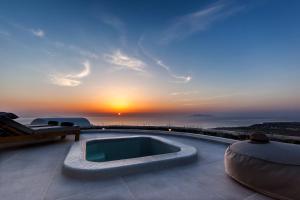 una piscina con tramonto sullo sfondo di Villa Vinea Santorini a Imerovigli