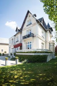 una grande casa bianca con un prato davanti di Villa 81 a Deauville