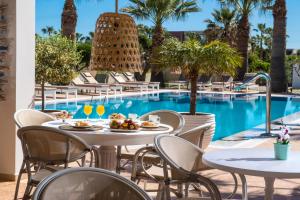 einen Tisch mit Speisen und Getränken neben einem Pool in der Unterkunft Ammos Boutique Apartments & Suites in Malia