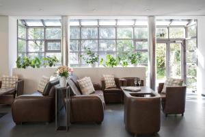 - une salle d'attente avec des canapés, des tables et des fenêtres dans l'établissement Hotel La Pergola, à Berne