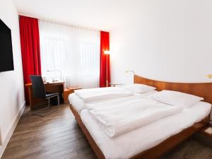 um quarto com uma cama grande e uma cortina vermelha em DORMERO Hotel Dresden Airport em Dresden