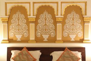 Tres árboles de Navidad en una pared sobre una cama en Hotel H R Palace, en Jaipur