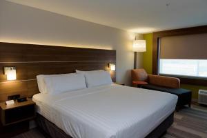 ein Hotelzimmer mit einem großen Bett und einem Stuhl in der Unterkunft Holiday Inn Express & Suites McKinney - Frisco East by IHG in McKinney