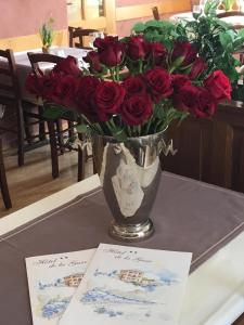 un vaso di rose rosse su un tavolo con due carte di Hôtel de la Gare a Yvonand