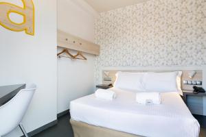 Cette chambre comprend un lit blanc et un lavabo. dans l'établissement Hotel Acta Laumon, à Barcelone