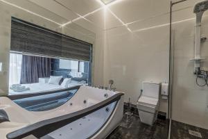 een grote badkamer met een bad, een bed en een toilet bij Hotel De KOKA in Skopje