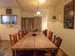 una sala da pranzo con tavolo e sedie in legno di J-Hoppers Hiroshima Guesthouse a Hiroshima