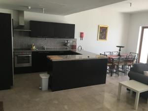 eine Küche mit schwarzen Schränken und ein Wohnzimmer in der Unterkunft Apartment in Jebel Sifah in As Sīfah