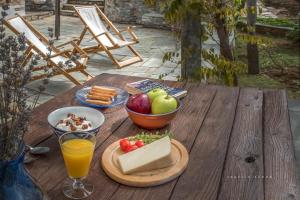 uma mesa de madeira com uma taça de fruta e um copo de sumo de laranja em Urania Traditional Stone House em Pinakátai