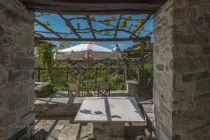 um pátio com uma mesa e um guarda-chuva em Urania Traditional Stone House em Pinakátai