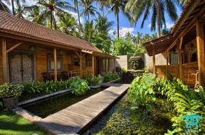 una casa con una pasarela de madera delante de ella en Benthos Bali Dive Resort, en Candidasa