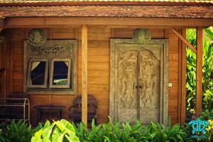 una casa de madera con una puerta tallada en Benthos Bali Dive Resort, en Candidasa