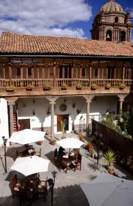 un patio al aire libre con mesas y sombrillas frente a un edificio en Unaytambo Boutique Hotel Cusco, en Cusco