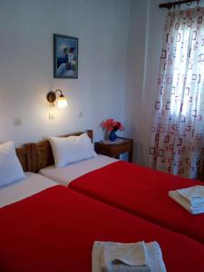 a bedroom with two beds with red sheets and a window at Sofia's Garden Studios in Skopelos Town